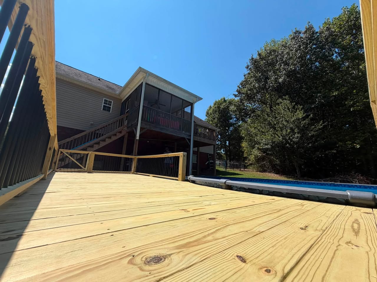 New wooden deck and black railings beside a swimming pool, shared by True North Co.